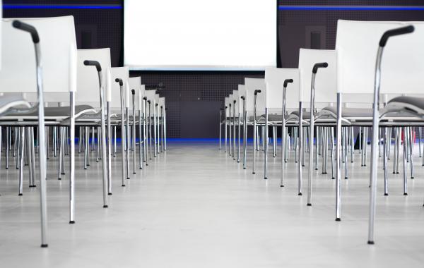 Low Angle Photography of Pile of Stainless Steel Chairs With Hanging Projector Canvas