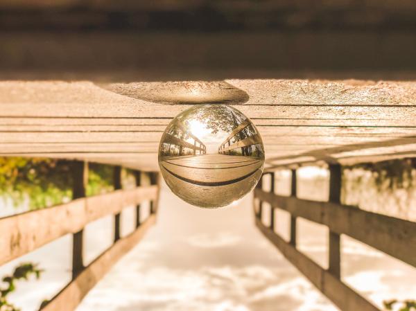 Macro Photography of Round Glass Ball on Top of Brown Wooden Dock