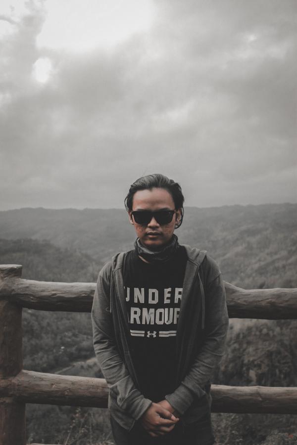 Man in Black Top and Grey Hoodie Jacket Standing Beside Brown Wooden