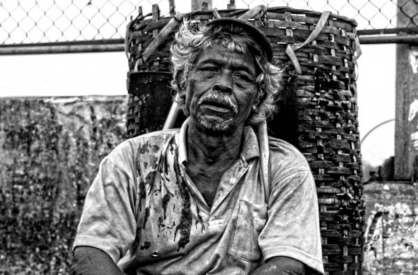 Man in Polo Shirt Sitting Near Brown Woven Basket Black and White Photography