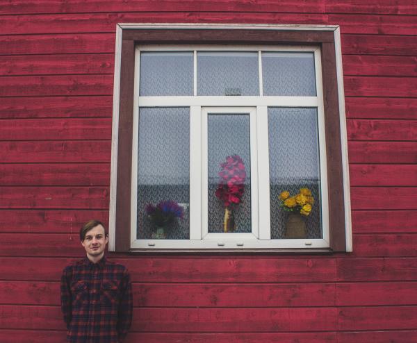 Man in Red and Black Dress Shirt Standing Beside a Red Wall