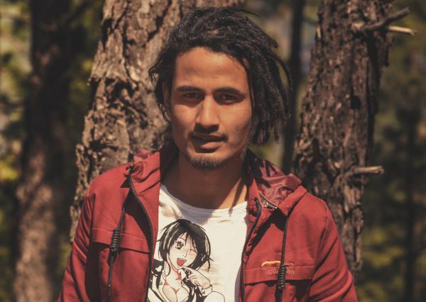 Man in Red Jacket Stands Near Trees at Daytime