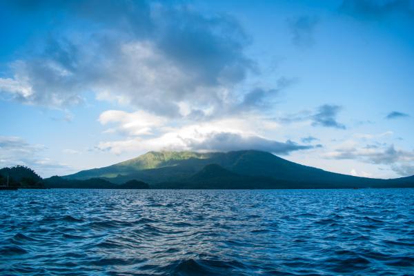 Ocean Near High Rise Mountain Cover With Fogs at Daytime