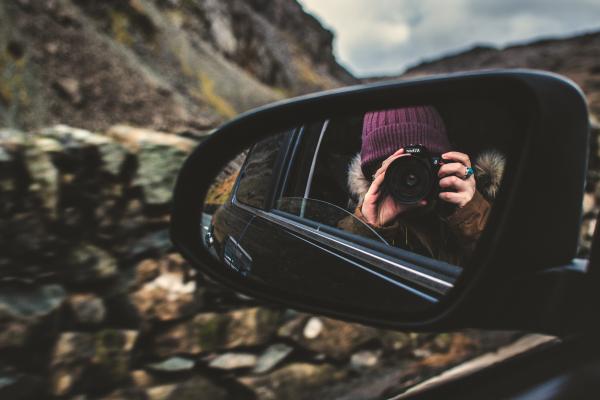 Person Holding Dslr Camera Reflected on Black Framed Wing Mirror