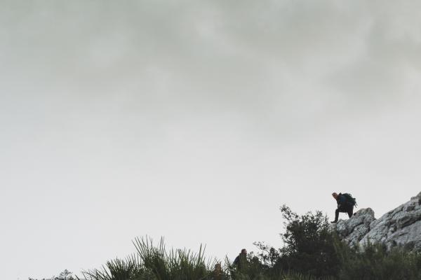 Person on Rocky Mountain Under White Cloudy Sky