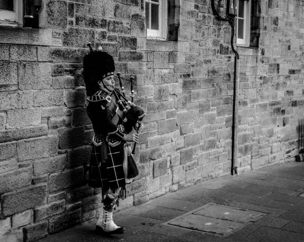 Person Using Bagpipes Near Wall in Grayscale Photography