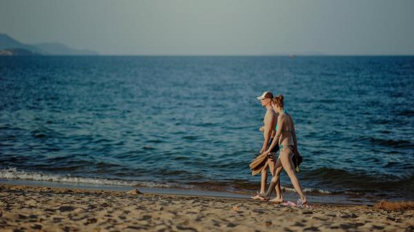 Photo of Man and Woman Walking on Seashore