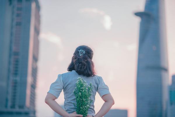 photo of Woman in Gray Top Holding Flowers on Her Back