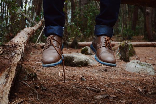 Photography of Person Wearing Brown Leather Shoes Near Brown Log on Green Forest during Daytime