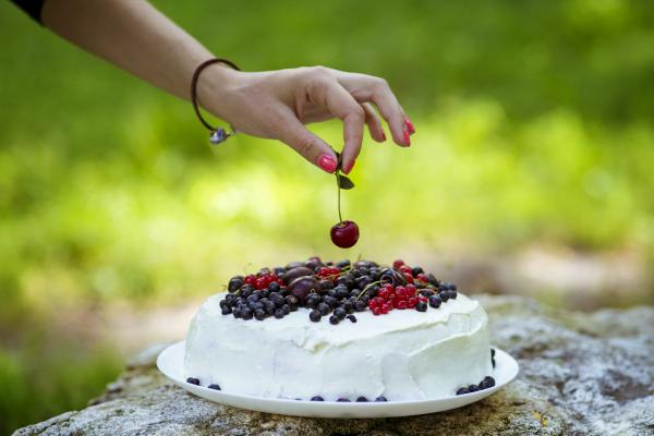 Putting cherry on the fresh berry cake