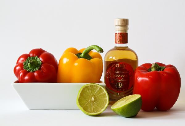 Red and Green Bell Pepper Inside White Ceramic Tray Near to Bottle and Lemon