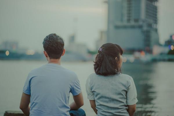 Selective Focus Photography of Man and Woman Watching Body of Water and Concrete Buildings