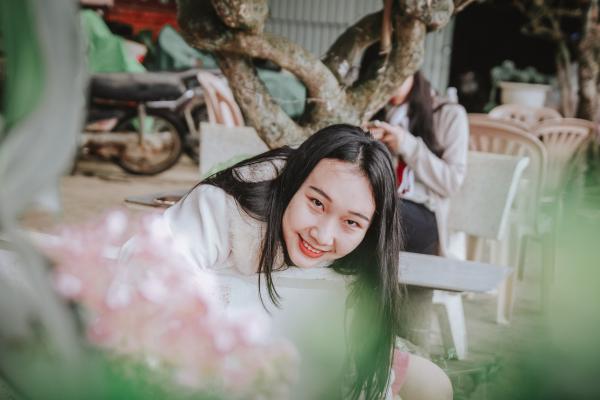 Selective Focus Photography of Woman Sitting on Chair Near Tree Branch