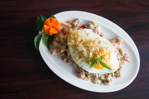 Serving of Marinated Meat With Sunny Side-up Egg and Slice of Carrot in Oval White Ceramic Plate