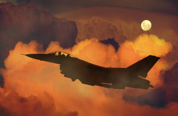 Silhouette of Fighter Plane Flying Through Clouds