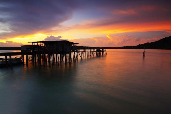 Silhouette of Wooden House Above Sea during Sunset