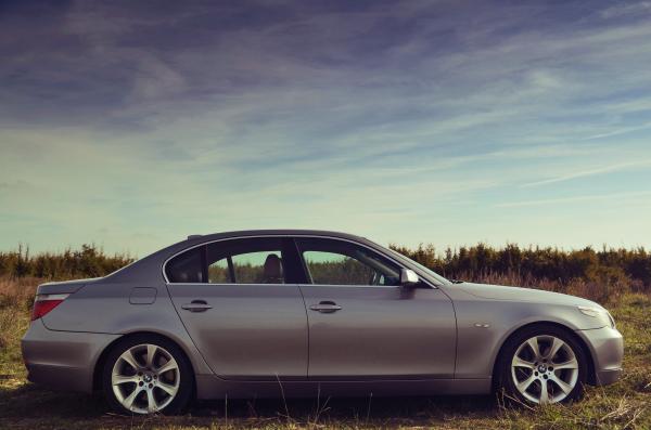 Silver Sedan Parked Far from Green Trees Under Blue Sky during Daytime