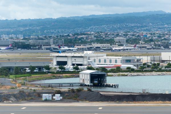 Small boat stored at cusp of lagoon at Honolulu International Airport