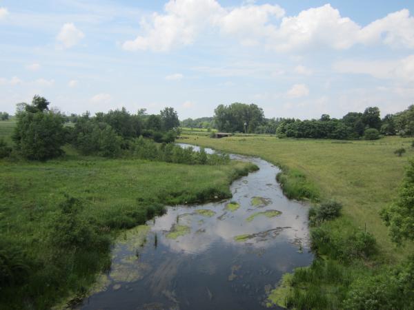 Small River With Farm In The Distance
