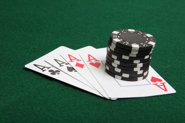 Stack of black poker chips on four aces.