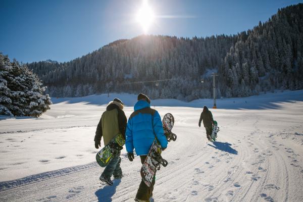 Three Person Holding Bubble Jacket Carrying Snowboards