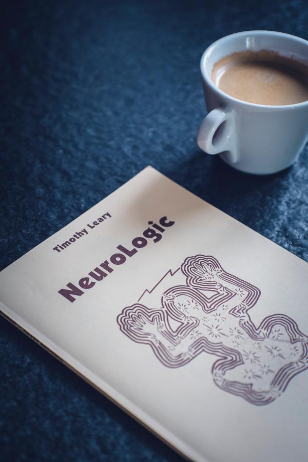 Timothy Leary's Neurologic Book Near White Ceramic Cup