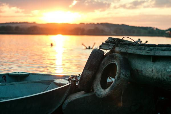 White Boat on Dock Near Two Auto Tires during Sunset