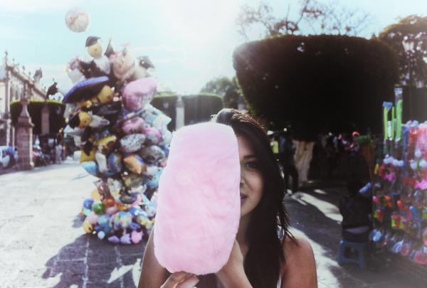 Woman Holding Cotton Candy With Balloons in Background