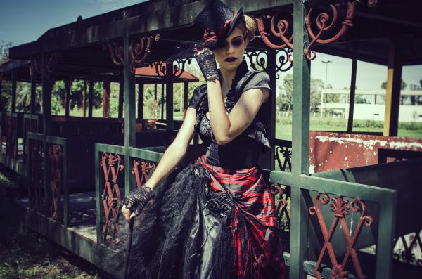 Woman in Black and Red Short-sleeved Dress Standing in Front of Green Steel Structure