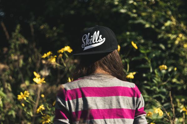 Woman in Gray and Pink Longsleeve Shirt Wearing Black Skill Printed Cap