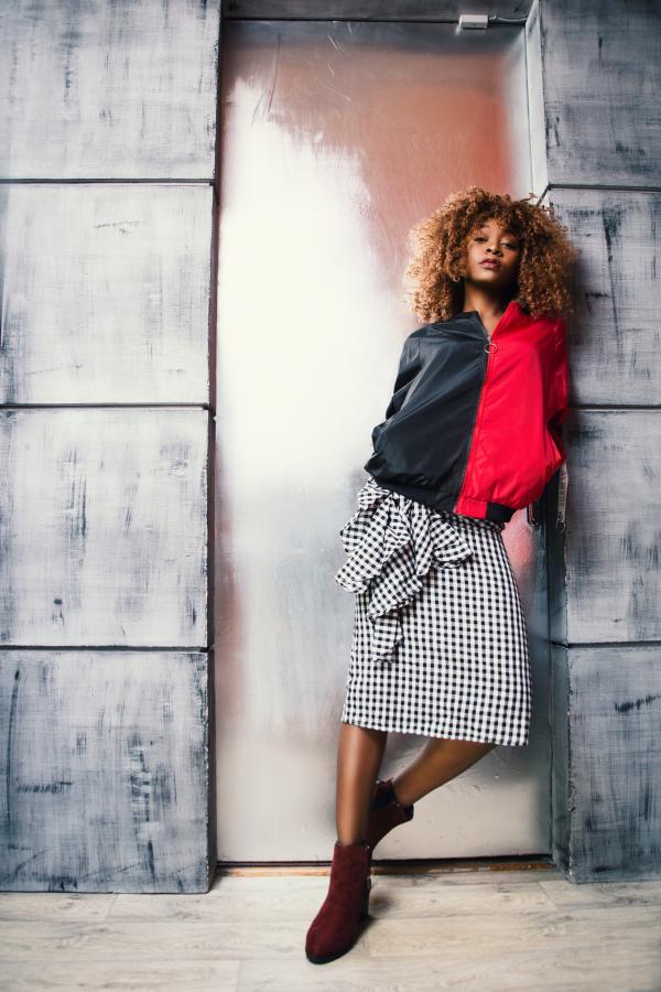 Woman in Red and Black Jacket Standing in Front of Brown Door
