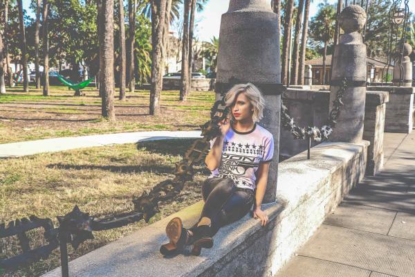 Woman in White and Black T-shirt and Pants Sitting on Beam