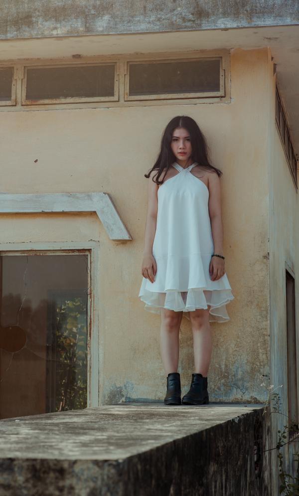 Woman in White Dress Standing on Concrete Wall