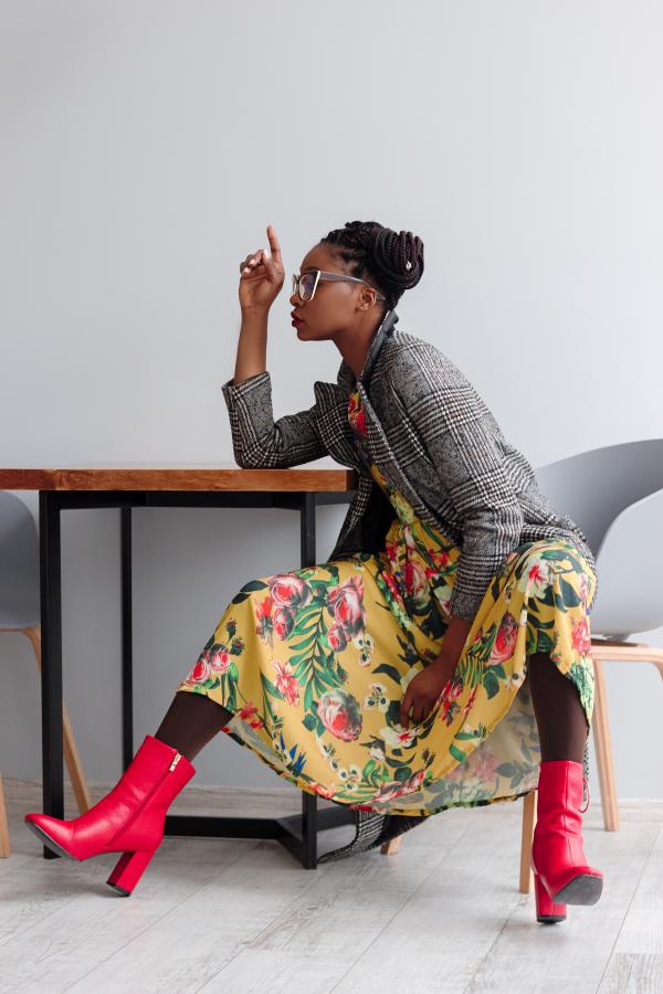 Woman Sitting on a Chair With Open Legs and Right Hand on Top of Wooden Table