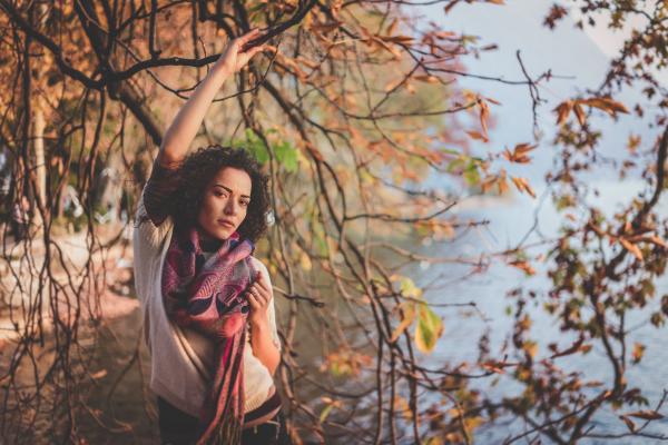Woman Standing Beside Bare Tree Near Body Of Water