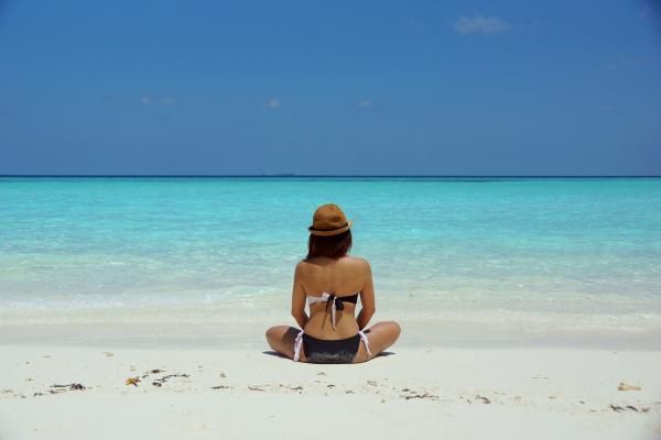 Woman Wearing Black and White Brassiere Sitting on White Sand