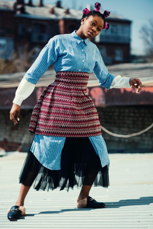 Woman Wearing Blue Long-sleeved Shirt and Red Skirt Standing on Roof
