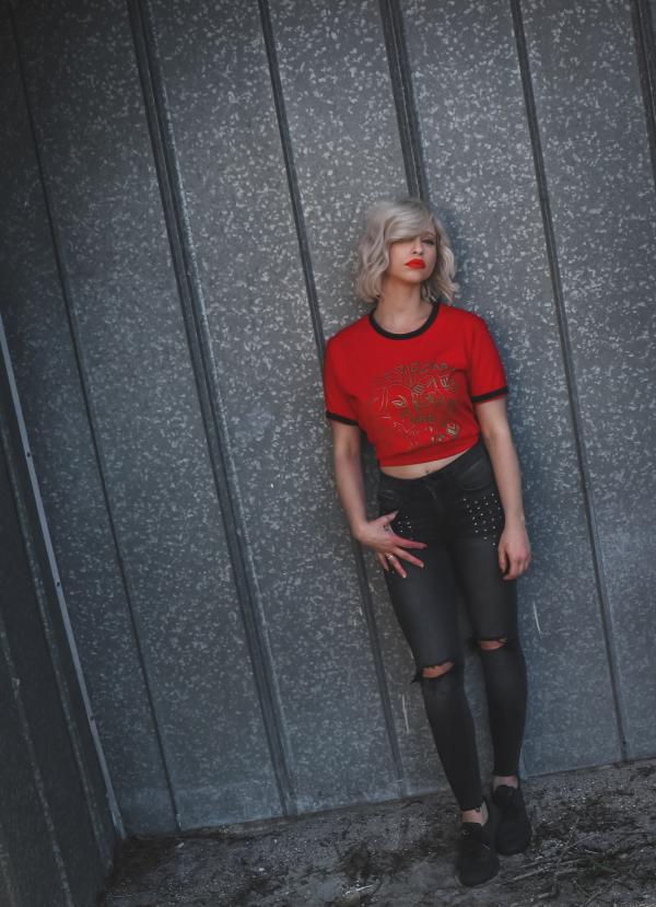Woman Wearing Red Shirt Leaning on Gray Wall