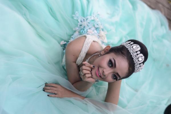 Woman Wears Teal Chiffon Gown and Crown