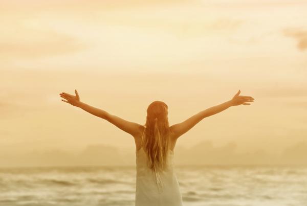 Woman with Raised Arms at Sunset on the Beach
