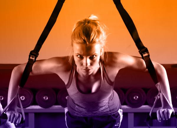 Young Attractive Woman Training with HTRX Fitness Straps in the Gym