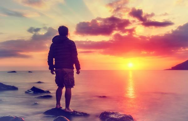 Young Man Watching the Sunrise at Rocky Beach